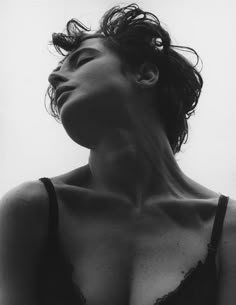 a black and white photo of a woman with her hair blowing in the wind, wearing a bra