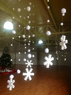 snowflakes are hanging from the ceiling in an empty room with wooden floors and lights