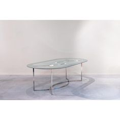 a glass table sitting on top of a cement floor next to a white wall in an empty room