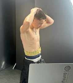 a shirtless man standing in front of a laptop with his hands on his head