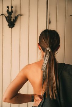 the back of a woman's head with a measuring tape around her neck and shoulder