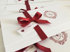 four wedding cards with red ribbon and monogrammed envelopes on white card stock