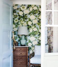 a room with a lamp, chair and flower wallpaper on the walls in it