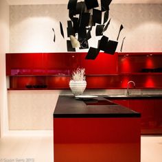 a modern kitchen with red cabinets and black counter tops, an island in the center