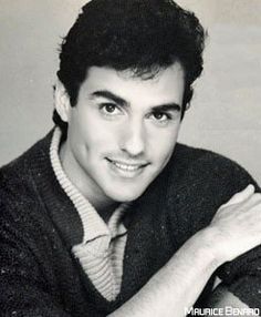 a black and white photo of a young man with his arms crossed, smiling at the camera