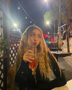 a woman sitting at a table with a drink in her hand