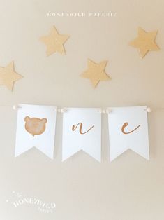 three little bunting banners with gold foil stars on them, one is for a baby's first birthday