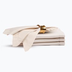 the folded napkins are white and have gold accents on them, along with a golden bell