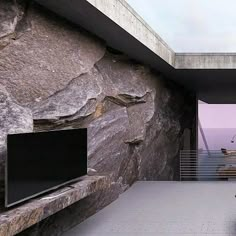 there is a large rock wall with a tv on it and stairs leading up to the top floor