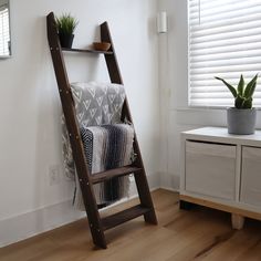 a ladder leaning up against a wall next to a potted plant on a shelf