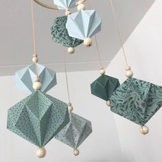 three origami ornaments hanging from the ceiling, one is blue and one is green