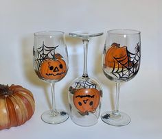 three wine glasses decorated with halloween pumpkins