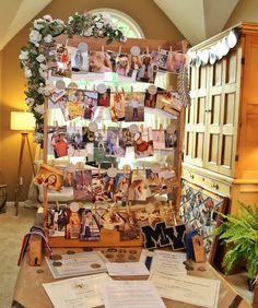 a table topped with lots of cards and pictures next to a wall filled with photos