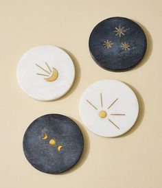 three black and white coasters with gold designs on them, one has a moon