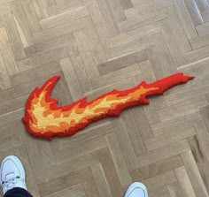 someone is standing on the floor next to a piece of art that looks like a fire