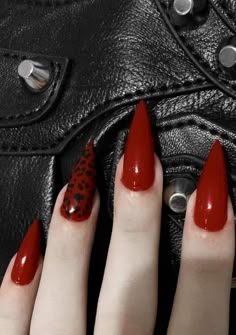 a woman's hand with red nail polish and leopard print on it