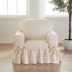 a chair with a skirt on it in front of a potted plant and window