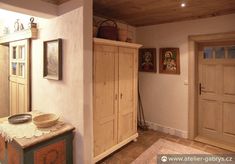 a wooden cabinet sitting in the corner of a room next to a wall with pictures on it