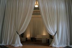 a room with white drapes open and lights on the ceiling in front of it