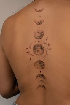 a woman's back with phases of the moon tattoo