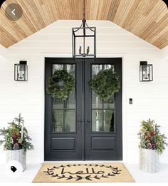 a black double door with two wreaths on the top and one hanging above it