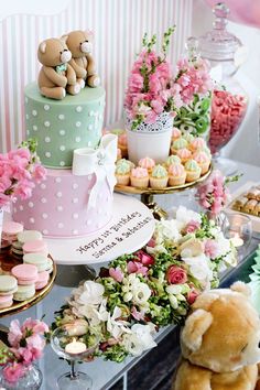 there are many different cakes and cupcakes on the table with teddy bears next to them