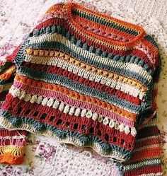 a crocheted sweater laying on top of a bed