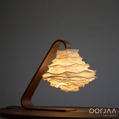 a lamp that is sitting on top of a wooden table next to a gray wall