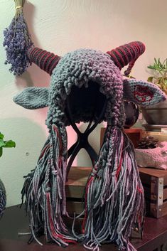 a knitted hat with horns and tassels on top of a wooden table