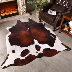 a cow hide rug in front of a fire place with a chair and fireplace behind it