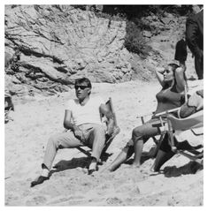 black and white photograph of people sitting on the beach