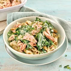 a bowl of pasta with salmon and spinach