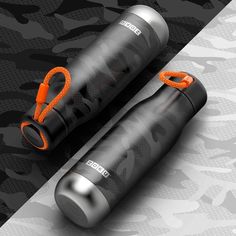 two black and orange water bottles sitting next to each other on top of a camouflage background