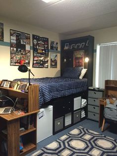 a dorm room with a bed, desk and computer on top of the dressers