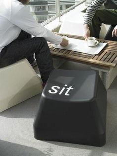 two people sitting at a table with a sign on it that says sit next to each other