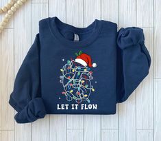 a blue sweatshirt with the words let it flow printed on it and a santa hat