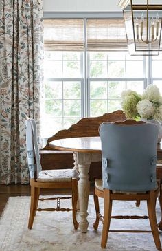 a dining room table with two chairs and a vase on top of it in front of a window