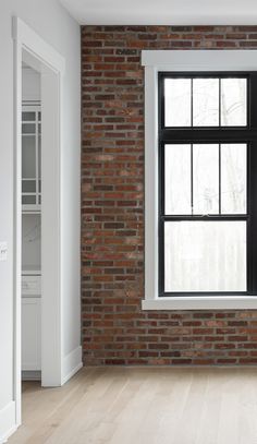 an empty room with a brick wall and white trim on the window sill is shown