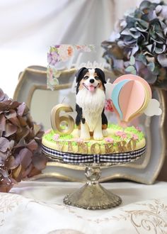 a dog figurine sitting on top of a cake next to flowers and decorations