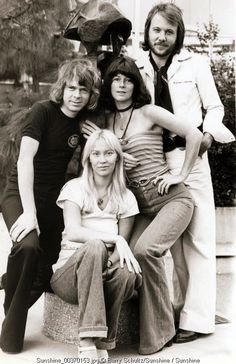 an old black and white photo of four people posing for the camera with their arms around each other