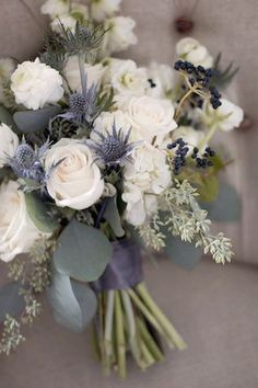 a bouquet of white flowers and greenery is sitting on the arm of a chair