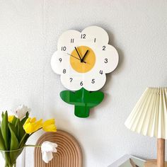 a clock that is on the wall above a vase with tulips in it