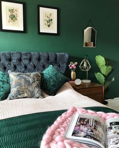 a bedroom with green walls and pictures on the wall above the bed, along with a pink blanket