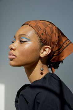 a woman with blue eyeshades and a head scarf on her head, looking off to the side