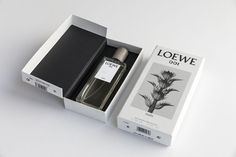 an open box with a perfume in it on a white table next to a black and white box