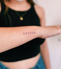 a woman's arm with the word yeshua written on it, in cursive font