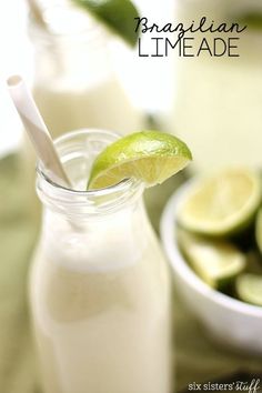 a close up of a drink in a glass with a straw and lime on the side