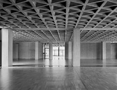 black and white photo of an empty room with wooden beams on the ceiling, in front of large windows