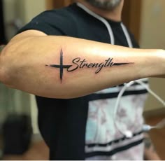 a man with a cross tattoo on his arm that says strength and the word strength is written in cursive font