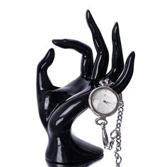 a black hand holding a pocket watch on a chain